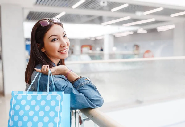 Счастливая женщина с сумкой в торговом центре, подарками, праздником и концепцией продажи одежды . — стоковое фото
