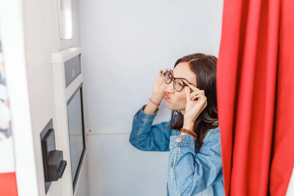 A woman is photographed and amused in a photo booth, making istant selfie photos for fun or for passport and documents — Stock Photo, Image