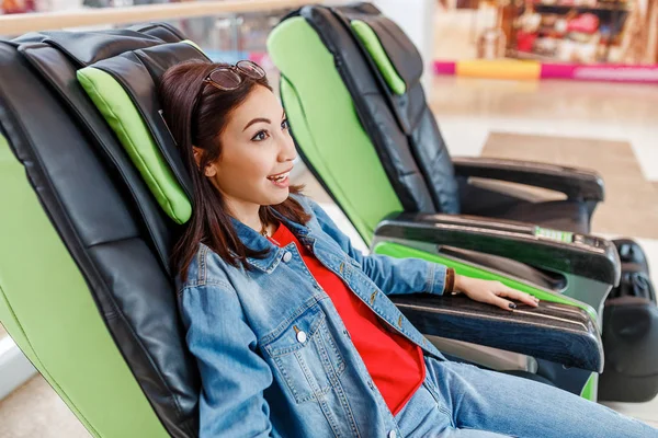 Młoda damo relaksujące po zakupach w fotel do automatycznego masażu w centrum handlowym — Zdjęcie stockowe