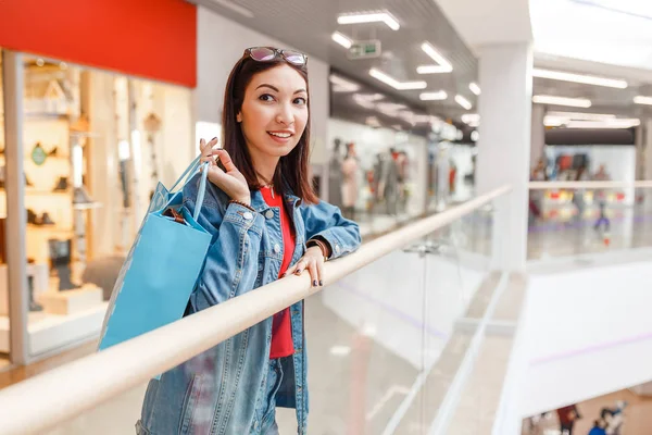 Счастливая женщина с сумкой в торговом центре, подарками, праздником и концепцией продажи одежды . — стоковое фото