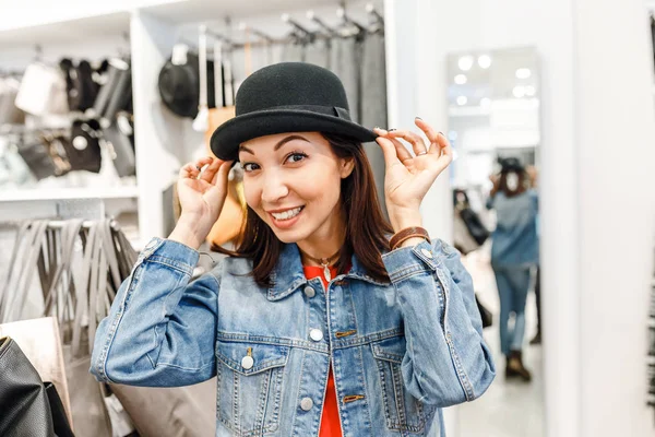 Женщина примеряет винтажную шляпу ретро в торговом центре — стоковое фото