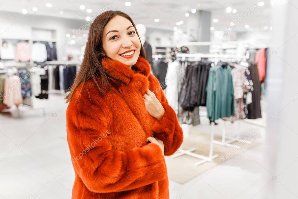 Asian woman, a buyer tries on a bright coat of artificial fur, the concept of shopping and leisure