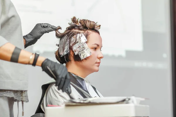 Coiffeur coloriage client femme cheveux dans salon de coiffure beauté studio, en utilisant brosse et feuille, teinture professionnelle et concept de traitement — Photo