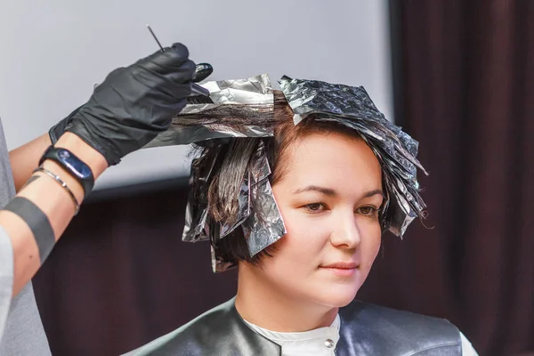 Coiffeur coloriage client femme cheveux dans salon de coiffure beauté studio, en utilisant brosse et feuille, teinture professionnelle et concept de traitement — Photo