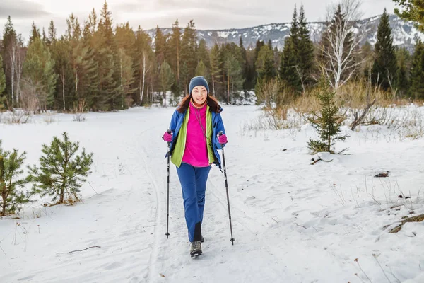 Mulher caminhante viajando com mochila e equipamento de trekking na floresta trilha de neve em montanhas, atividade de inverno e conceito de recreação — Fotografia de Stock