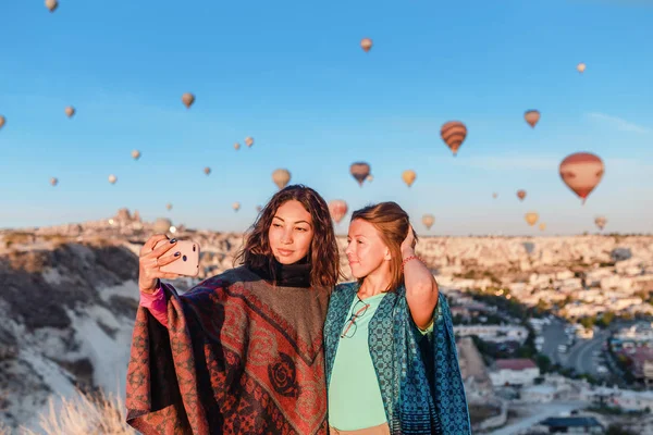 Reisende genießen die Aussicht auf das Tal und machen ein Selfie am Telefon mit wunderbaren Ballons, die über das Tal von Kappadokien in der Türkei fliegen — Stockfoto