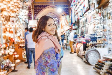 Istanbul'da Kapalı Çarşı pazarda sayısız dükkan arasında yürüyen kadın turist. Alışveriş ve seyahat Türkiye kavramında