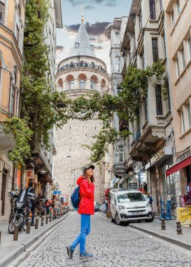 29 Eylül 2017, Istanbul, Türkiye: Galata Kulesi ve eski şehir Istanbul 'un, Türkiye'de caddenin yakınında yürüyen genç mutlu turist kadın