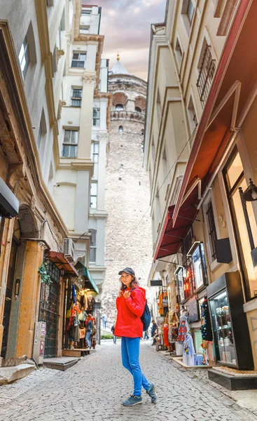 Joven mujer turista feliz caminando cerca de la Torre Galata y la calle en el casco antiguo de Estambul, Turquía —  Fotos de Stock