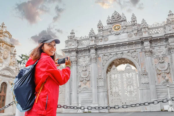 Mujer turista tomando fotos en su teléfono inteligente en la puerta de entrada principal del Palacio Dolmabahce —  Fotos de Stock