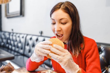 Kadının modern fastfood restoranda hamburger elinde eldiven eller