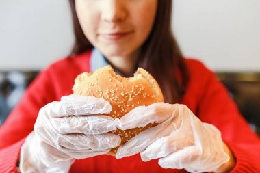 Kadının modern fastfood restoranda hamburger elinde eldiven eller
