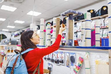 Genç kadın müşteri oyuncak evde beslenen hayvan dükkanında tırmalamak kedi arıyorum