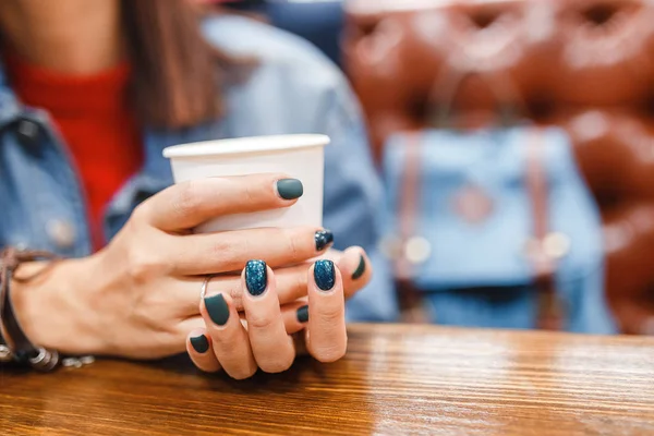 Женщина пьет кофе из одноразовой чашки в кафе — стоковое фото
