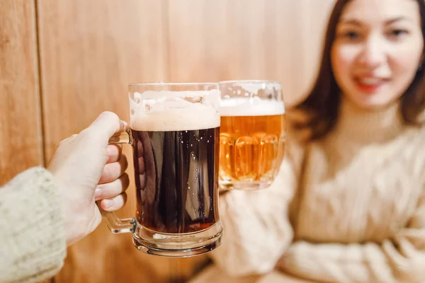 Las manos masculinas y femeninas tazas con cerveza oscura y lager hecha a mano en un auténtico pub o bar — Foto de Stock