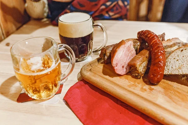 Two mugs of beer and pork snack on the table in czech pub — Stock Photo, Image