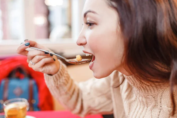 Молода жінка їсть суп з ложкою — стокове фото