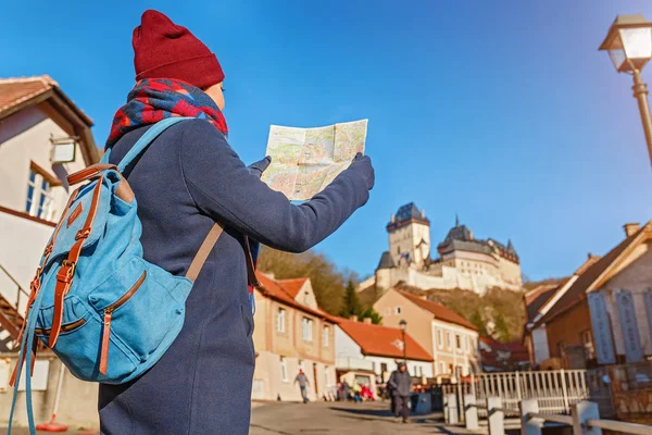 07 grudnia 2017 r., Karlštejn, Czech Republic: Kobieta dla podróżujących z plecakiem, patrząc na mapę, w pobliżu średniowiecznych gotycki zamek Karlstejn w Czeskiej Reoublic w zimie — Zdjęcie stockowe