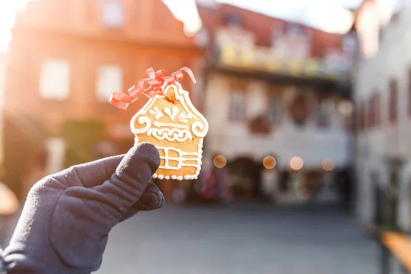 Mão com casa de gengibre gostoso tradicional no fundo da rua Chesky Krumlov decorado para o Natal — Fotografia de Stock