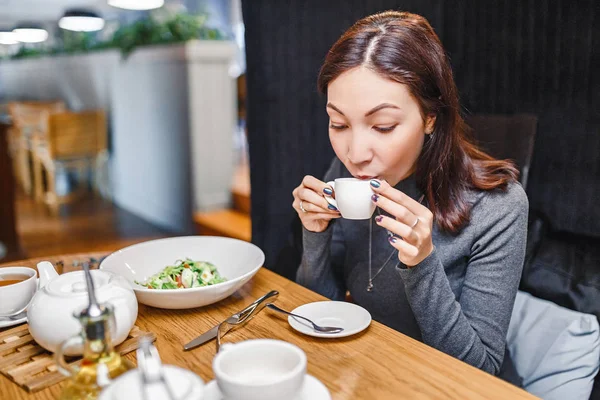 Joven mujer oriental bebiendo café fuerte aroma en un café — Foto de Stock