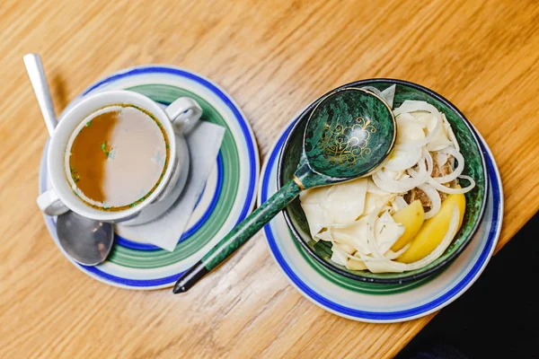 Elesh Orta Asya Mutfağı işkembe çorbası erişte ile geleneksel bir tabak ve otantik Ulusal desenlerle süslenmiş bir ahşap tabak sebze olduğunu — Stok fotoğraf