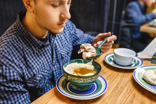 Man eating traditional asian soup from patterned wooden plate — Stock Photo, Image