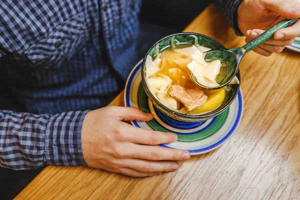 Man eating traditional asian soup from patterned wooden plate — Stock Photo, Image