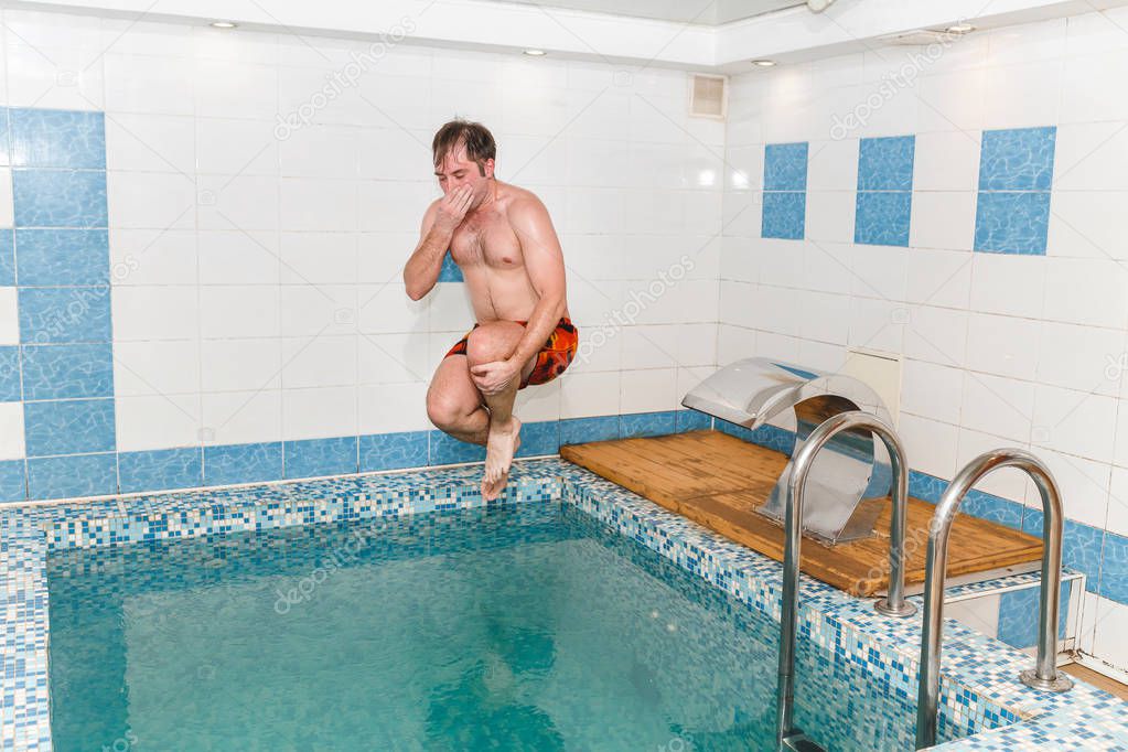 Funny portrait of man jumping in small swimming pool indoors