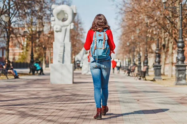 Hipster dziewczynka z plecakiem, chodzenie na wyłączonej z ruchu kołowego ulicy, tylnych widok — Zdjęcie stockowe