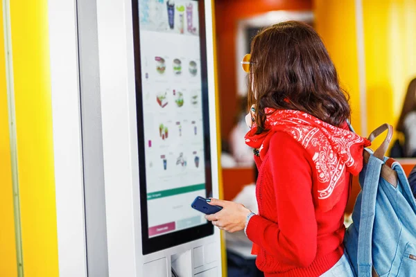 Asijské žena bederní objednává jídlo na dotykové obrazovce samoobslužné stroje elektronické menu v restauraci fastfood — Stock fotografie