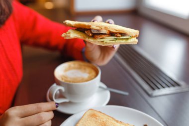 Sandviç ve kahve beyaz Kupası tahta masada Kahvaltı sabah kafede tutan el