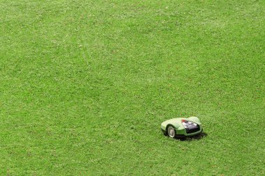 Parktaki çimlerin üzerinde çalışan robot çim biçme makinesi.