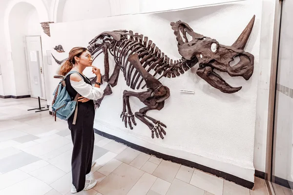 07 Srpen 2019, Mnichov, Německo: Ženské studentky při pohledu na zkamenělou kostru dinosaura ceratopse, dávného předka nosorožce v Muzeu paleontologie v Mnichově — Stock fotografie