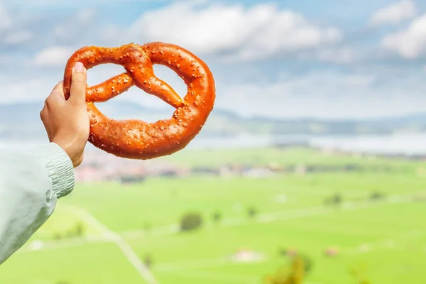 Bavarian and german cuisine - female hand holding traditional pretzel bakery snack