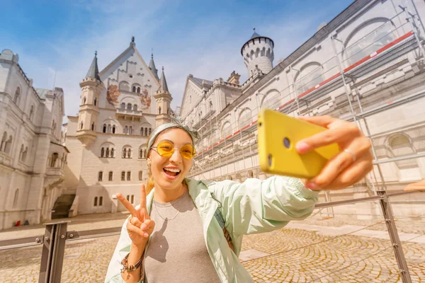 Ασιάτισσα φωτογραφίζει selfie στο κάστρο Neuschwanstein στην εσωτερική αυλή. Ταξιδιωτικοί προορισμοί σε Γερμανία και Ευρώπη έννοια — Φωτογραφία Αρχείου