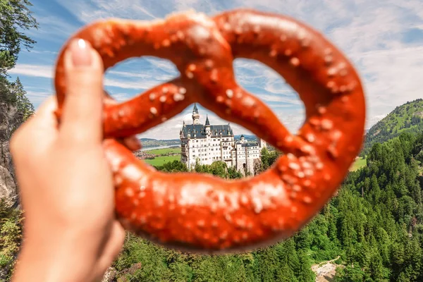 Tradiční bavorský brezel nebo preclík na pozadí slavného německého hradu Neuschwanstein. Koncept cestování a cestovního ruchu — Stock fotografie