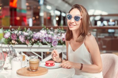 Mutlu Asyalı kadın kafede lezzetli kurabiyeler tadıyor. Kahvaltı ve Fransız mutfağı konsepti