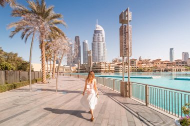 Dubai 'de çeşmelerin yanında yürüyen mutlu turist kız. Tatil ve gezi konsepti