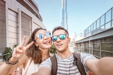 Two friends a man and a woman travel in Dubai and take a selfie photo against the background of the skyscrapers. Tourism in UAE