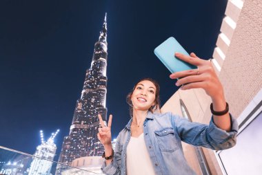 26 Kasım 2019, Uae, Dubai: Dünyanın en yüksek binasının önünde selfie çeken mutlu Asyalı kadın - Burj Halife