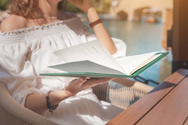 Gülümseyen kız terasta dinlenirken barda ya da restoranda menü okuyor.