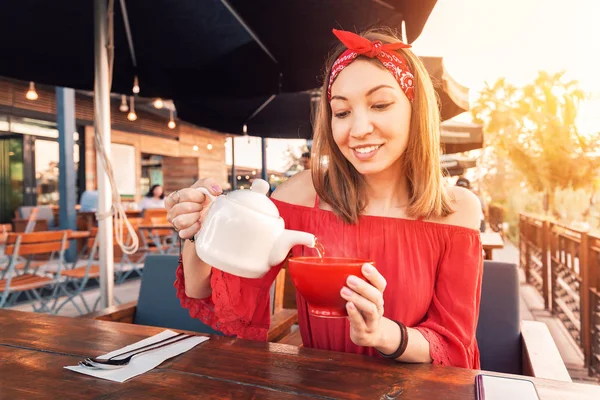 Азиатская девушка наливает чай из чайника в кафе — стоковое фото
