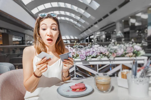 Kafası karışmış bir kız kahvaltının parasını bir kafede nasıl ödeyeceğini düşünüyor. — Stok fotoğraf