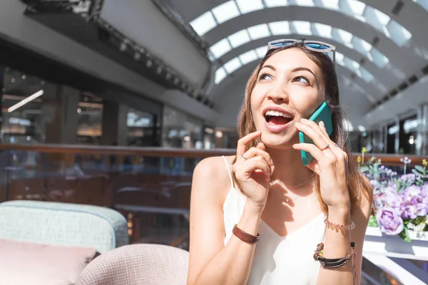 Asian woman with funny face expression talking by phone in cafe — Stock Photo, Image