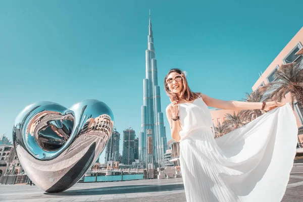 Chica feliz en vestido blanco en la plaza cerca de Dubai Mall y el famoso rascacielos Burj Khalifa —  Fotos de Stock