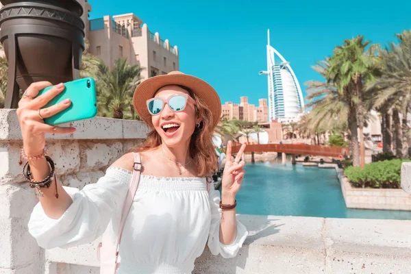 Счастливая девушка фотографируется на смартфоне на фоне городского пейзажа в Дубае с отелем Burj al Arab — стоковое фото