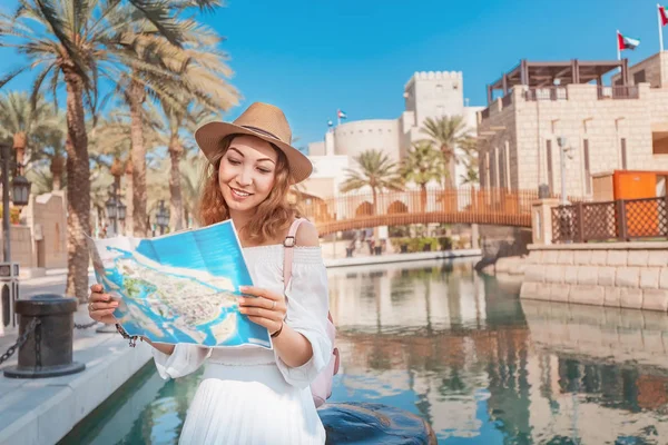 Veselá dívka stojící s mapou poblíž Madinat Jumeirah Hotel and Mall. Cestování a cestovní ruch v Dubaji a Spojených arabských emirátech — Stock fotografie