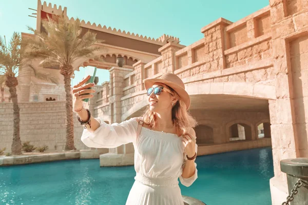 Šťastná asijské dívka v bílých šatech přičemž selfie foto na její smartphone na pozadí středovýchodním starém městě. Cestování a dovolená v Dubaji a arabských emirátech koncept — Stock fotografie
