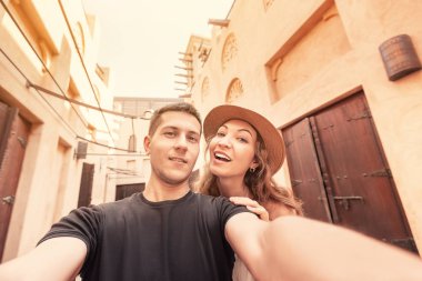 A happy couple takes a selfie against the backdrop of ancient Arabic architecture in the old town of Dubai. Honeymoon journey concept