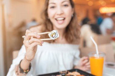 Yemek katında Bento yerken yemek çubuklarıyla suşi yiyen bir kız.
